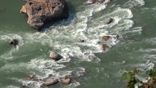 Ein Blick von oben auf die Stromschnellen und Felsen in einem Fluss, während das Wasser fließt.