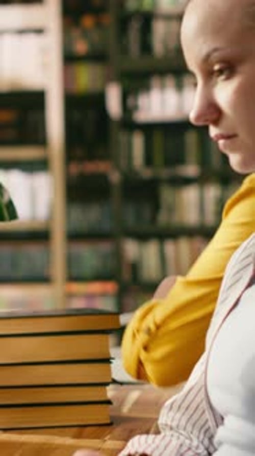Vidéo verticale : un étudiant discute de son devoir avec un tuteur au bureau de la bibliothèque universitaire