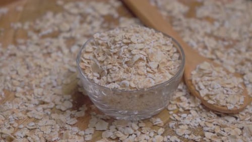 Oatmeal Flakes in Bowl on Wooden Surface