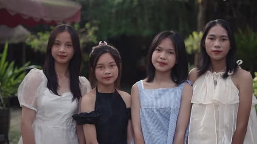 Quatro jovens adolescentes asiáticas em vestidos de verão e maquiagem posam para a câmera sorrindo lado a lado