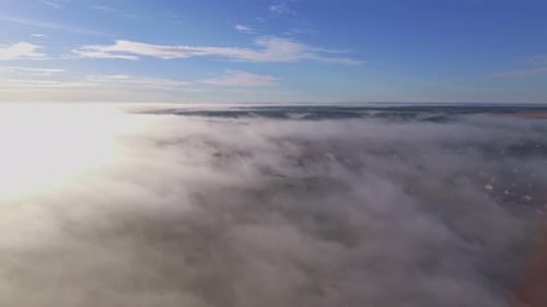 Winding River and Settlement Surrounded by Morning Fog Illuminated Sunrise Light. Aerial