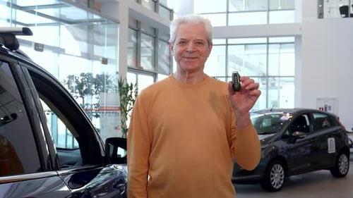 Senior Man Gives a Thumbs Up While Holding Car Keys at the Dealership