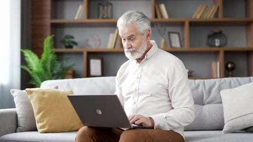 Senior Man Using Laptop Computer On Couch