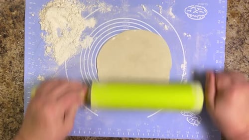 Rolling out round pieces of raw dough with a rolling pin to make patties. Top view.