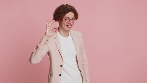 Young Adult Makes 'Okay' Gesture on Pink Background