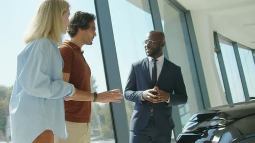 Car Salesman Shakes Hands with Customer in Dealership