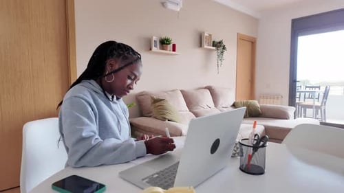 Young Adult Working at Table with Laptop and Notes