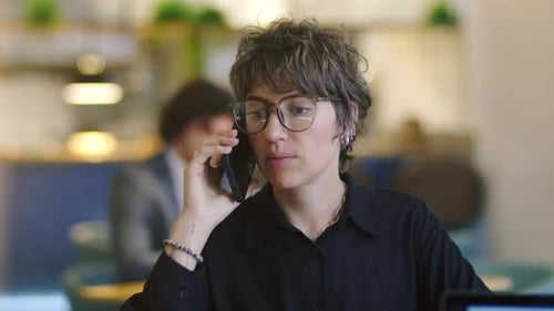 Young Businesswoman Having Phone Conversation in Cafe