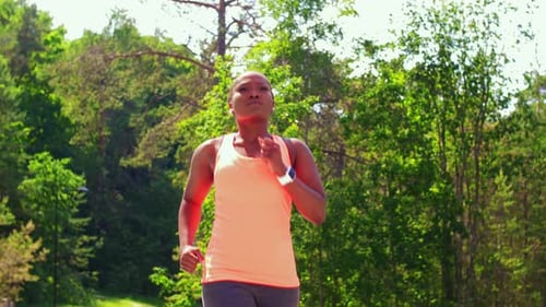 Young african american woman running through a forest on her fitness journey