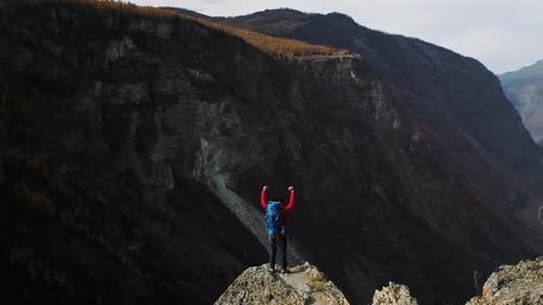 Hiker Celebrating Reaching Mountain Peak with Arms Raised