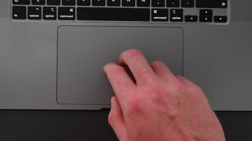 Ein Laptop-Benutzer bewegt den Pfeil auf dem Bildschirm mit den Finger auf dem taktilen Trackpad