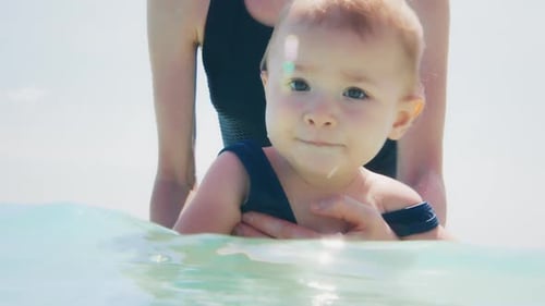 Mother swims with infant baby in the tropical sea