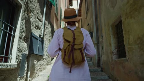 Young Attractive Woman Tourist in a Hat with a Backpack Wanders the Street of the Old City While