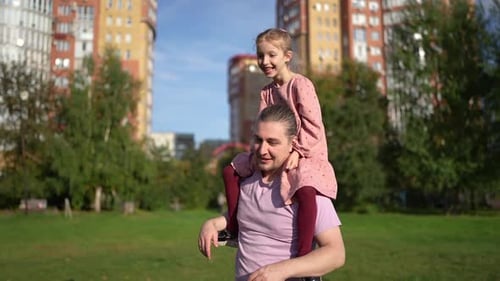 Father Gives Daughter a Piggyback Ride in Park