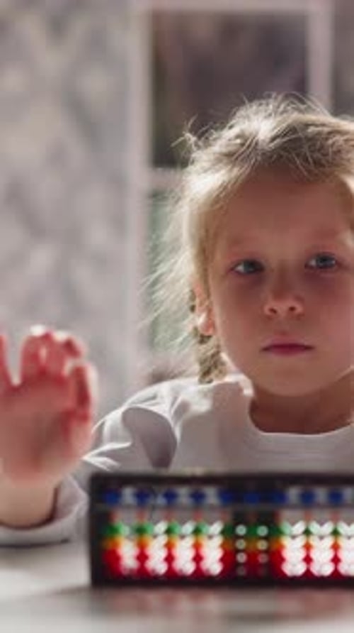 Unhappy Little Girl Does Finger Training Near Abacus at Desk