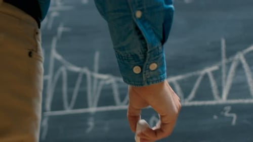 Brilliant Young Academic Finishes Writing Complex Mathematical Formula/ Equation on the Blackboard.