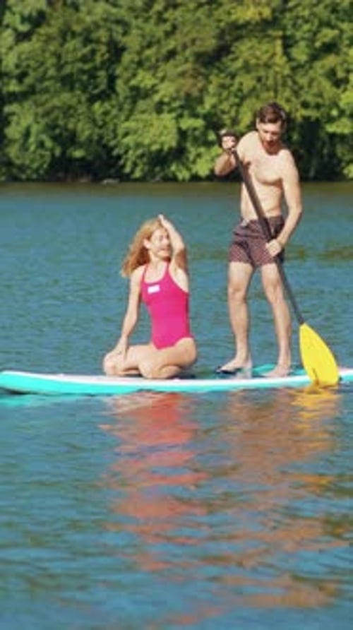Couple paddle boarding and playing on a lake