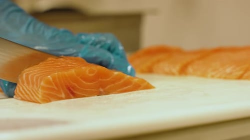 Slow-mo of a juicy piece of salmon being sliced by a chef at a restaurant and then placed amongst ot