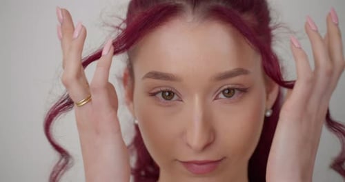 Close up of beautiful young caucasian girl touching pink purple hair looking into camera. Slow motio