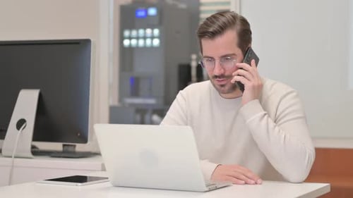 Man Talking on Phone While Working at Desk