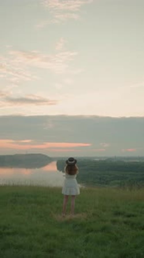 Woman in White Dress Contemplating at Sunset By Tranquil Lake