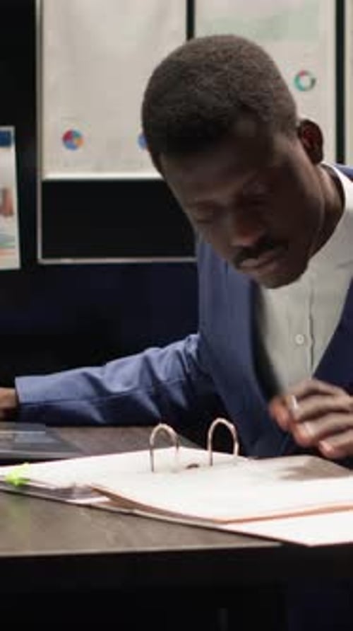 Man Reviews Paperwork at Desk in Modern Office