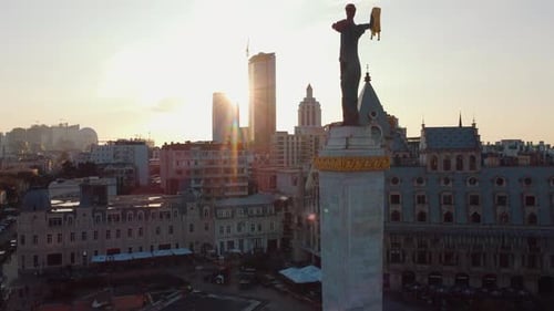 Circular aerial view from drone in rays of sun at sunset around statue in Batumi