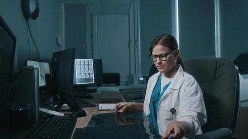 Female Radiologist Examining X-ray Pictures during Workday in Medical Office