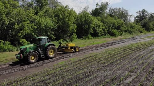 Grader works with tractor and levelling the field road