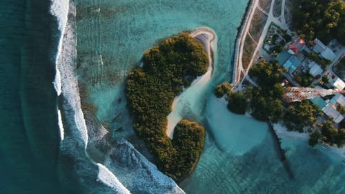green island with white sand beach waves and blue lagoon