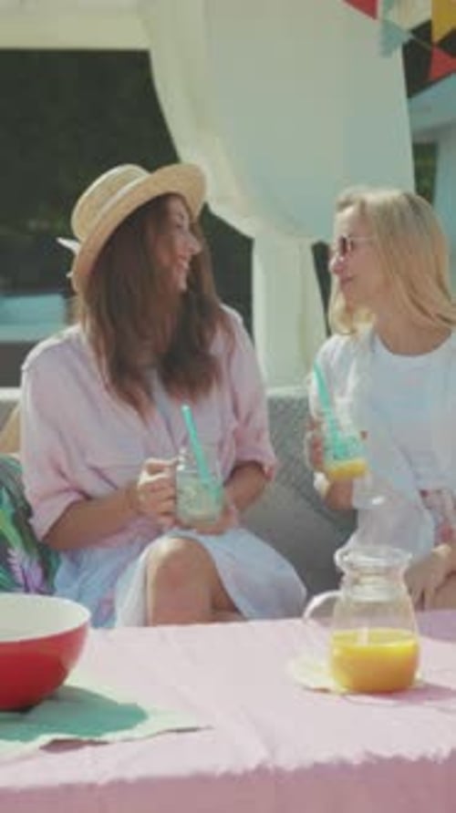 Des amis détendus partageant du jus dans le jardin, deux amis prenant un brunch décontracté en plein air avec boissons