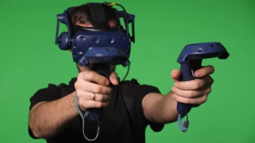 A Man Uses Virtual Reality Glasses to Play in a Studio on a Green Background