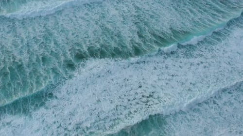 Aerial view of breaking waves on the shore, shot from done above