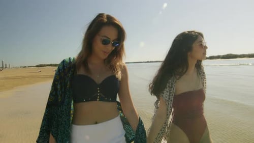 Two Beautiful Young Caucasian Women Holding Hands, Walking on the Beach, Laughing