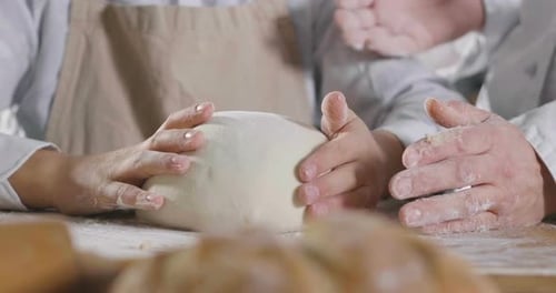 Close up of a baker kneading with his hands to prepare the bread to put in the oven. Concept of: a