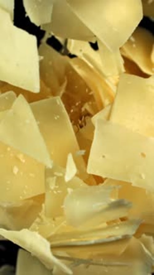 Parmesan Cheese Flakes Fly Upwards on a Black Background Filmed on a Highspeed Camera at 1000 Fps