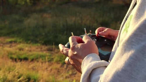 Hands Operate Drone Remote Control in Field