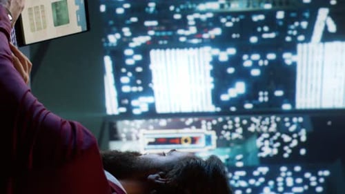 Man Looks at Screens in Dark Futuristic Room