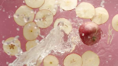 Viele rote Äpfel auf rosafarbenem Hintergrund wurden im Aquarium im Wasser gefilmt