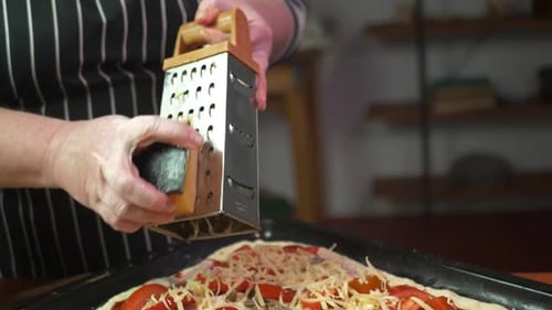 A Woman Grates Cheese on a Homemade Pizza