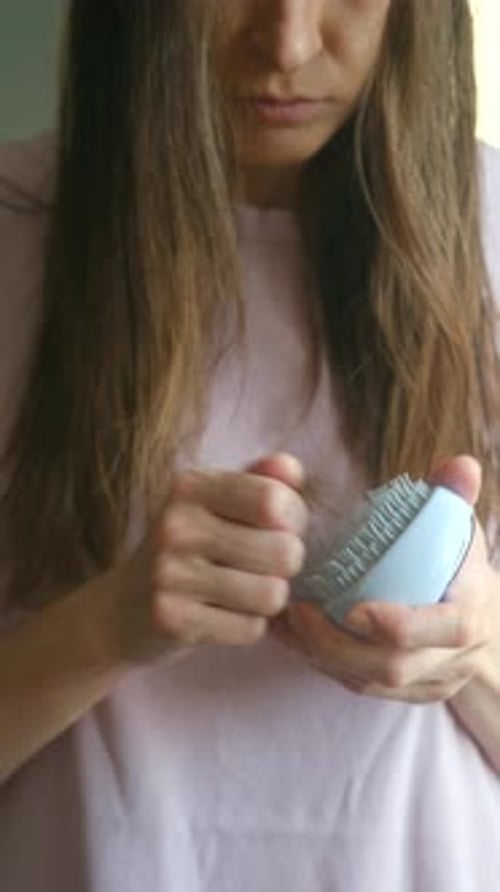 Worried Woman Showing Hair Loss Problem on a Brush
