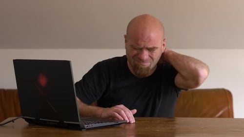 Lockdown, smart working - young man at computer with stiff neck
