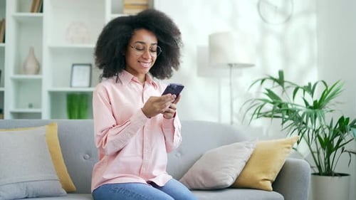 Young Woman Using Smartphone on Couch Indoors