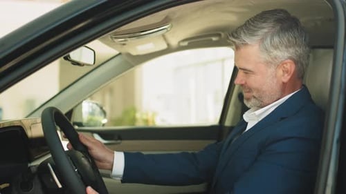 Smiling Man Sitting in Modern Car at Dealership
