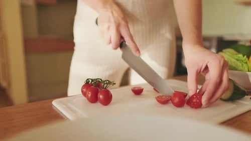 Close-up of young woman's hands cutting tomatoes making salad at home in the kitchen