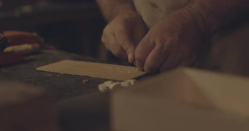 Artisan Hands Cutting Leather at Workbench Close Up