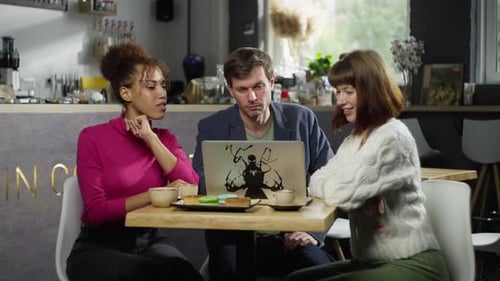 A Group of Friends Discuss Business at a Computer in a Cafe