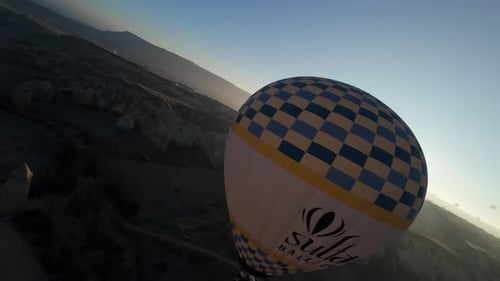 FPV Drone Circling Around a Hot Air Balloon with People Hovering Low Over Love Valley at Sunrise in