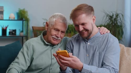 Senior and Young Adult Looking at Cell Phone