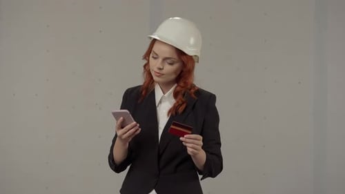 A Woman Architect Pays for a Purchase in an Online Store Using a Smartphone and a Credit Card